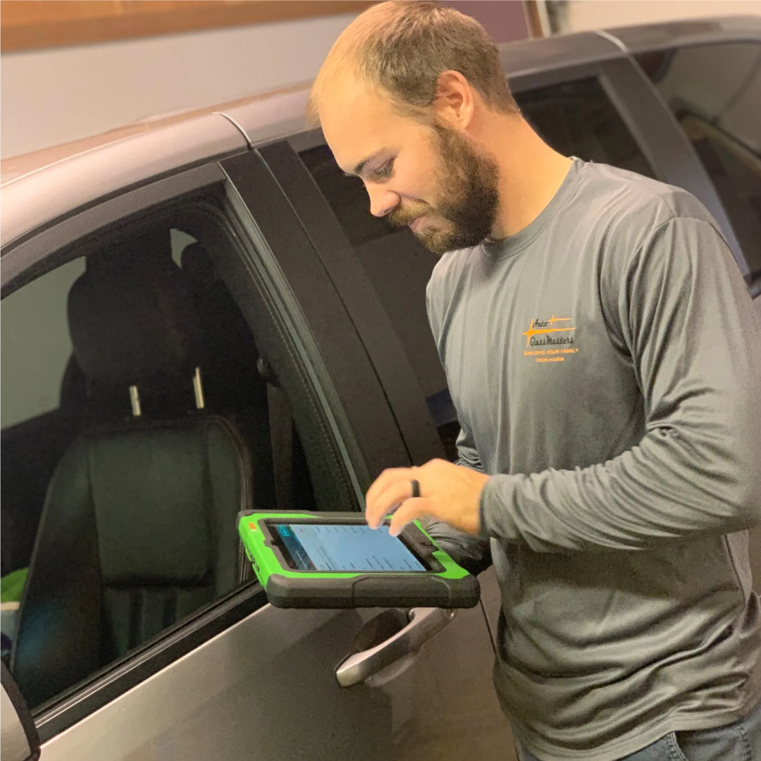blob-2e302ba A man uses a tablet near a car window.