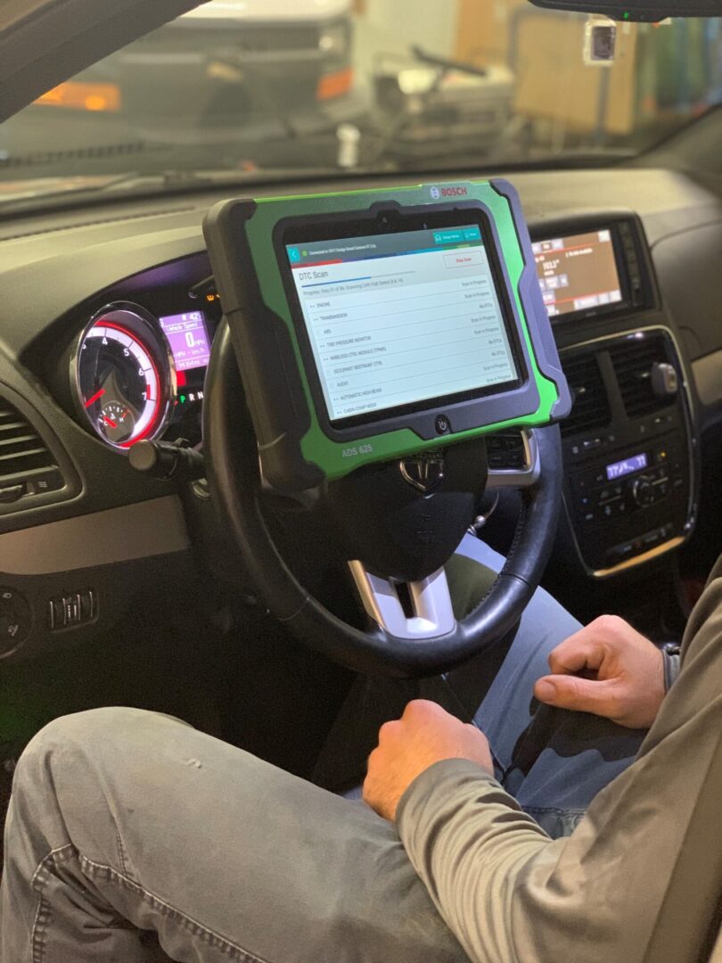 Justin2 A person holding a diagnostic tool inside a car's cockpit.